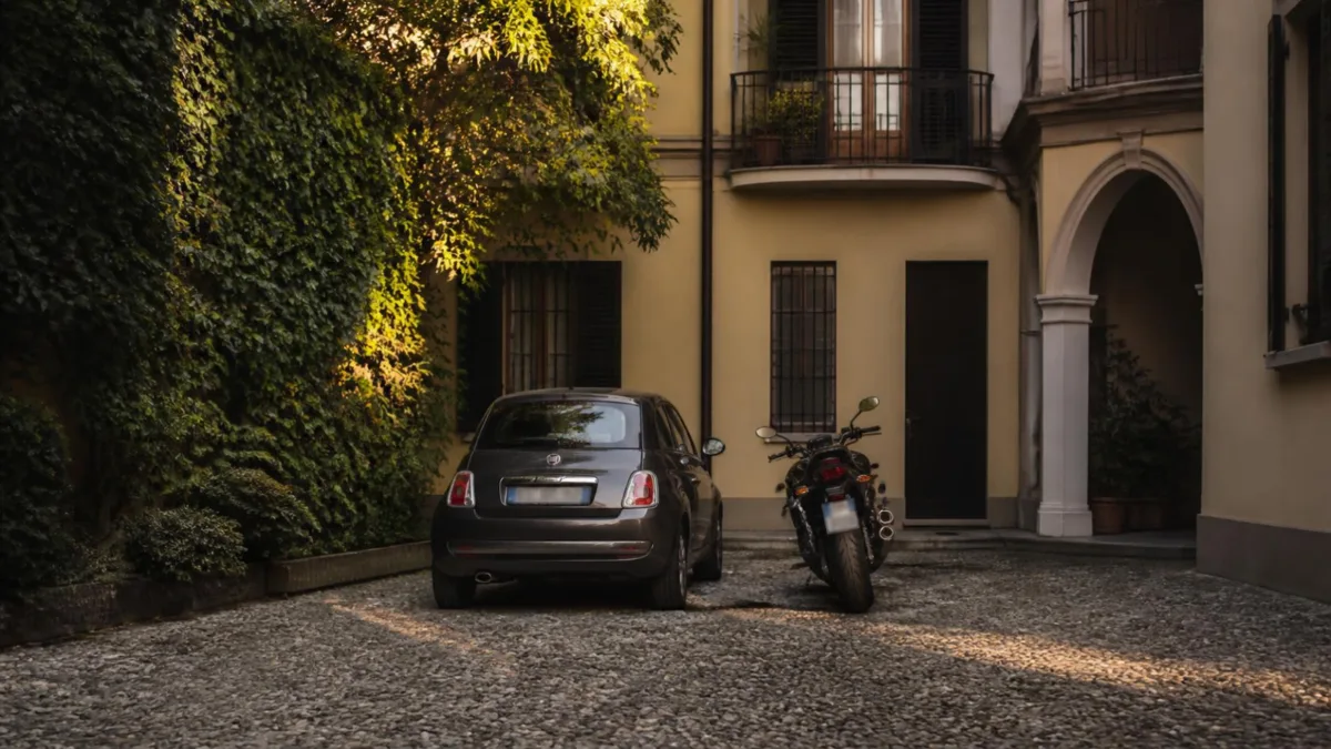 Auto e moto parcheggiate una accanto all'altra in un cortile condominiale