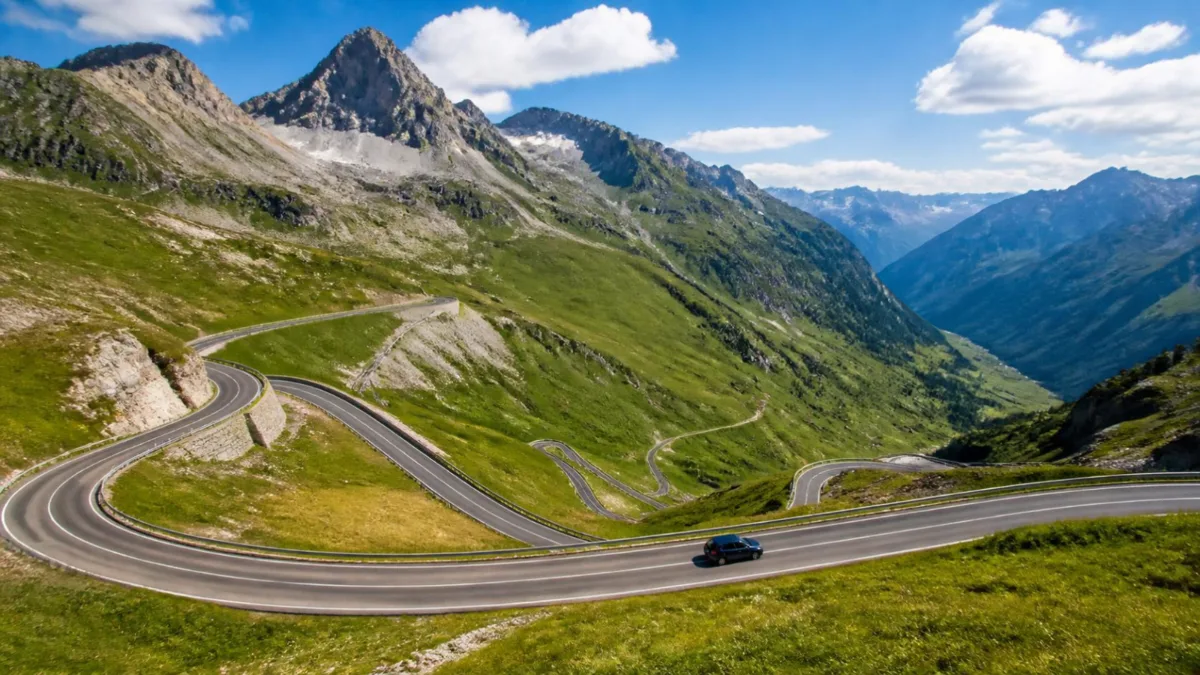 Passo alpino verso il confine Auto che sale lungo i tornanti di un passo alpino vicino al confine, tra prati verdi e cime rocciose