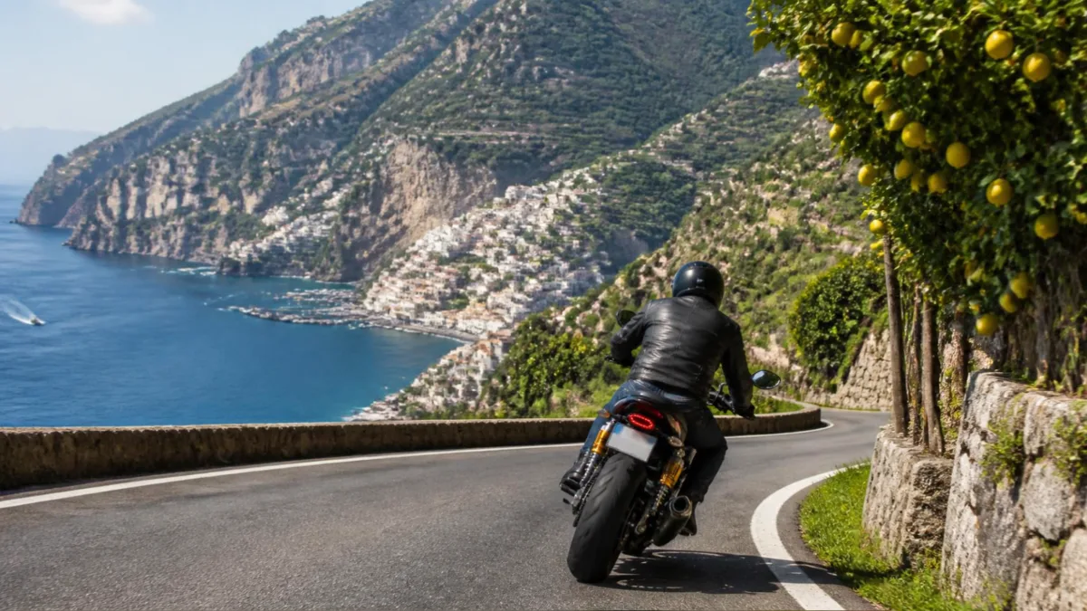 Motociclista di spalle che affronta una curva su una strada panoramica della Costiera Amalfitana